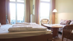 A hotel room with a bed, a small table, a chair, and a view of the outdoors.