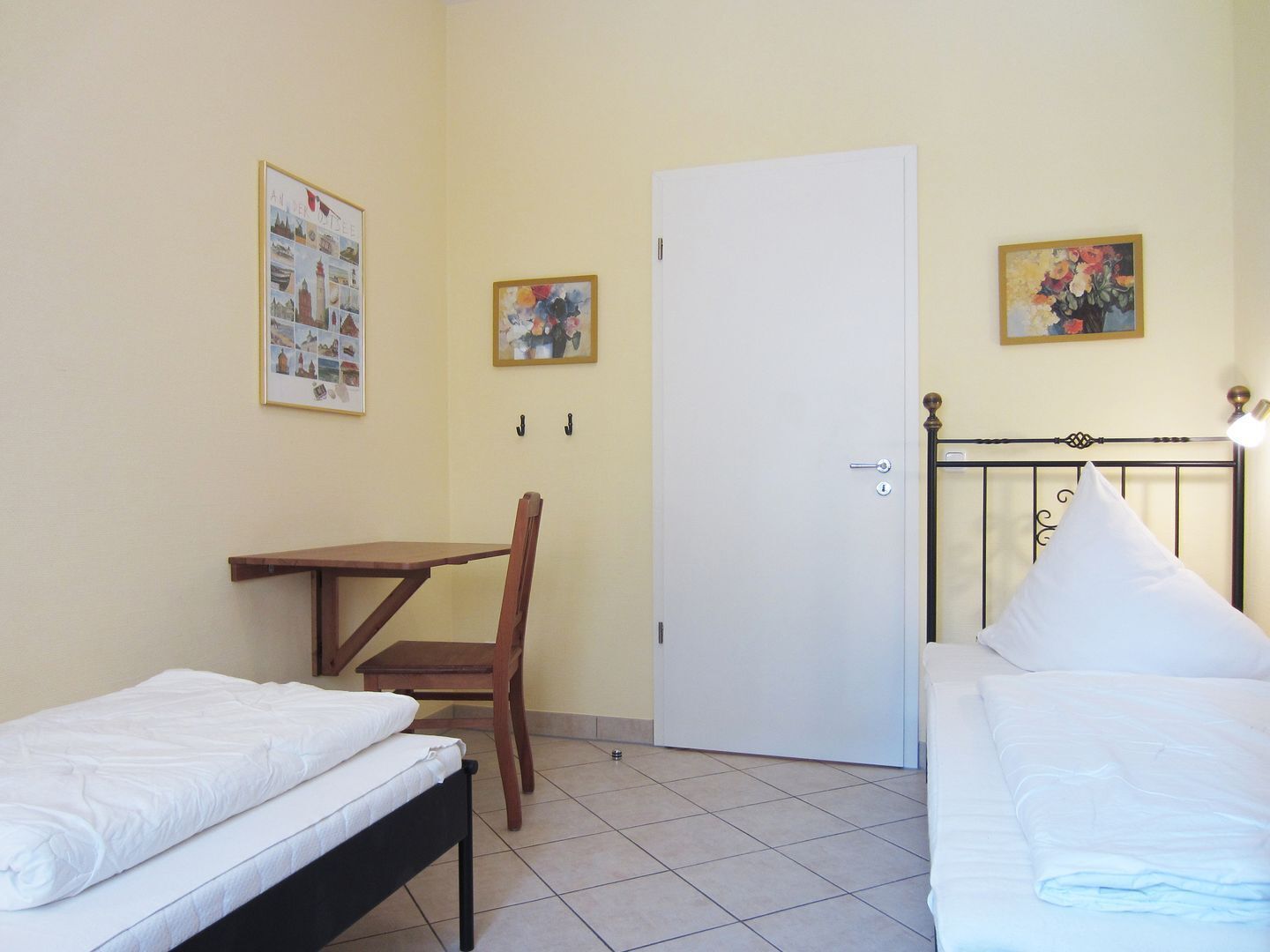 Una habitación con dos camas, un escritorio y dos sillas.