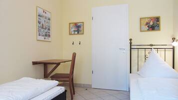 Una habitación con dos camas, un escritorio y dos sillas.