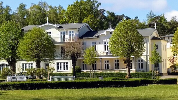 A row of multi-story residential buildings with a well-maintained lawn in the foreground.