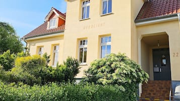 Ein Gebäude mit einer gelben Fassade, mehreren Fenstern und einer Tür mit der Nummer 22.