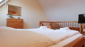 Un dormitorio con una cama grande, un aparador de madera, una silla, un televisor y un espejo.