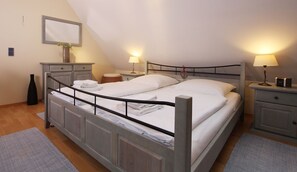 Une chambre à coucher avec un lit, des tables de chevet, une lampe, un miroir et un vase.