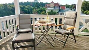 Une terrasse en bois avec deux chaises et une table, une bouteille et des verres.