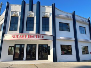 A theater with a marquee reading 'SUNSET THEATER' and a modern architectural design.