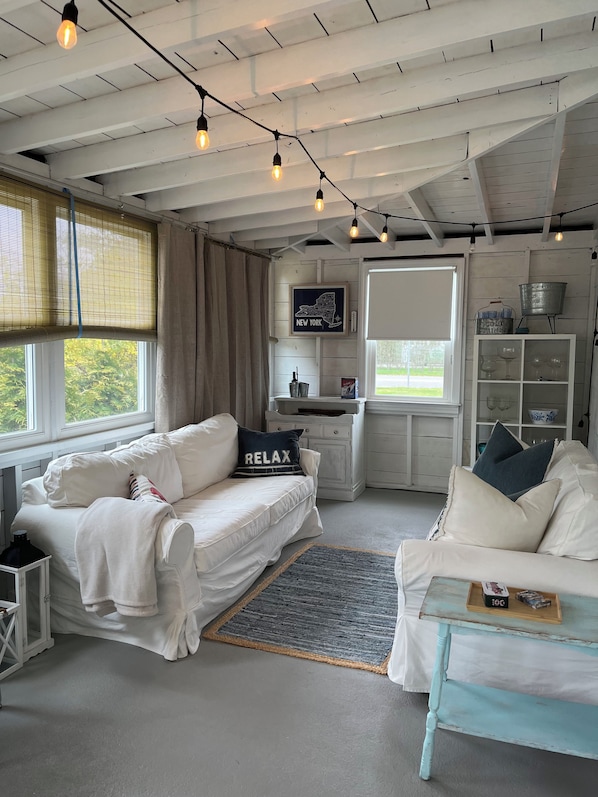 A cozy room with a white sofa, a small table, and a window with blinds.