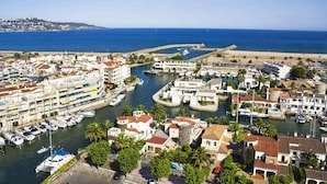 Un pueblo costero con un puerto deportivo, edificios con tejados rojos y una vista despejada del mar.