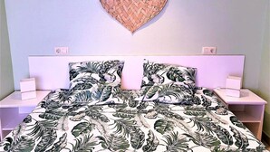 Um quarto com uma cama, duas mesas de cabeceira, uma decoração de parede em formato de coração e um edredom estampado com flores.
