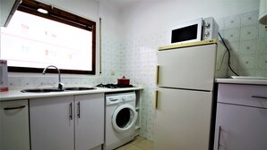 Uma cozinha compacta equipada com máquina de lavar, micro-ondas e frigorífico.