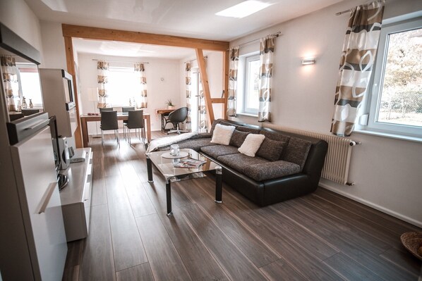 Ein modernes Wohnzimmer mit Sofa, Couchtisch und Essbereich.