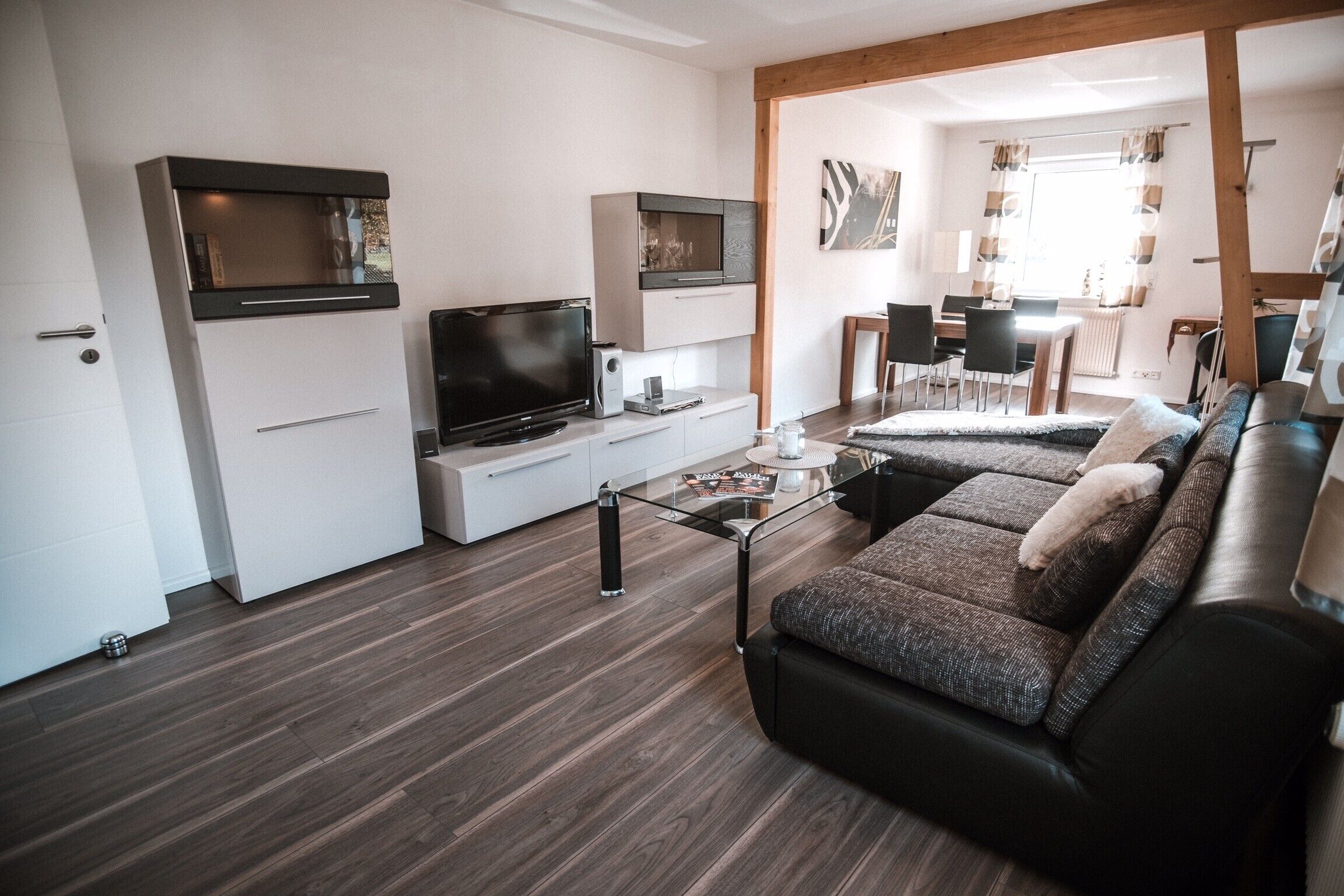 Ein modernes Wohnzimmer mit einer Couch, einem Fernseher und einem Glastisch.