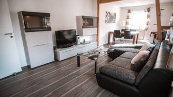 Ein modernes Wohnzimmer mit einer Couch, einem Fernseher und einem Glastisch.