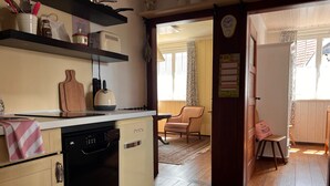La cuisine est équipée d’un lave-vaisselle, d’une bouilloire et d’une machine à café, qui sont tous placés sur le plan de travail. Une chaise se trouve dans la pièce adjacente.