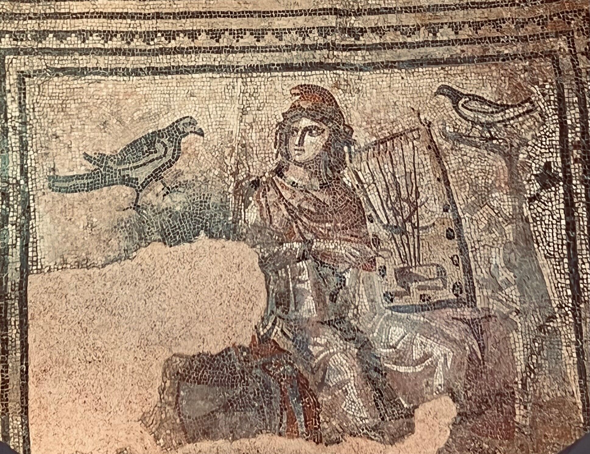 Ein Mosaik mit einer zentralen Figur, möglicherweise einer Gottheit, umgeben von Vögeln und einer Leier.
