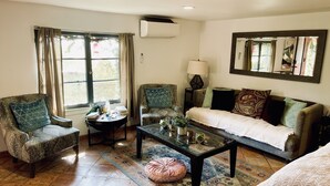 Una sala de estar con sofá, sillones, una mesa de centro y alfombra.