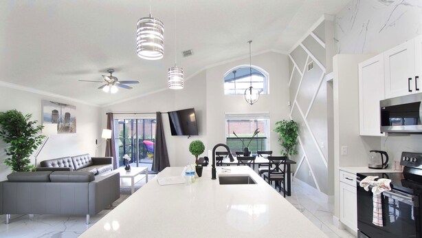 A modern kitchen with a central island, white cabinetry, and a black oven. - The Modern/Luxe Vacation • Heated Pool •  Disney (Davenport)