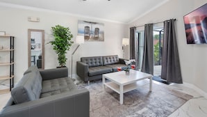 A modern living room with a grey sofa, a white coffee table, and a ceiling fan. - The Modern/Luxe Vacation • Heated Pool •  Disney (Davenport)