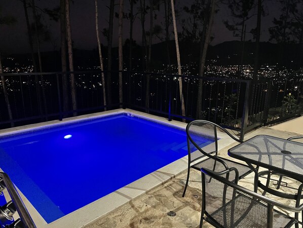 A swimming pool with a view of the city at night.