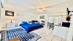 A bedroom with a bed, a nightstand, a desk, a chair, and a ceiling fan. - Beach Tide Motel - #6 Studio 1 King bed (Hollywood)