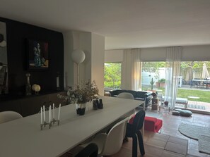 Un espace repas comprenant une longue table, des chaises, un vase avec des fleurs, un chandelier et un tableau accroché au mur.