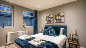 Ein Schlafzimmer mit einem großen Bett, einem Heizkörper, einem Fenster mit Vorhängen und zwei Wandbildern.