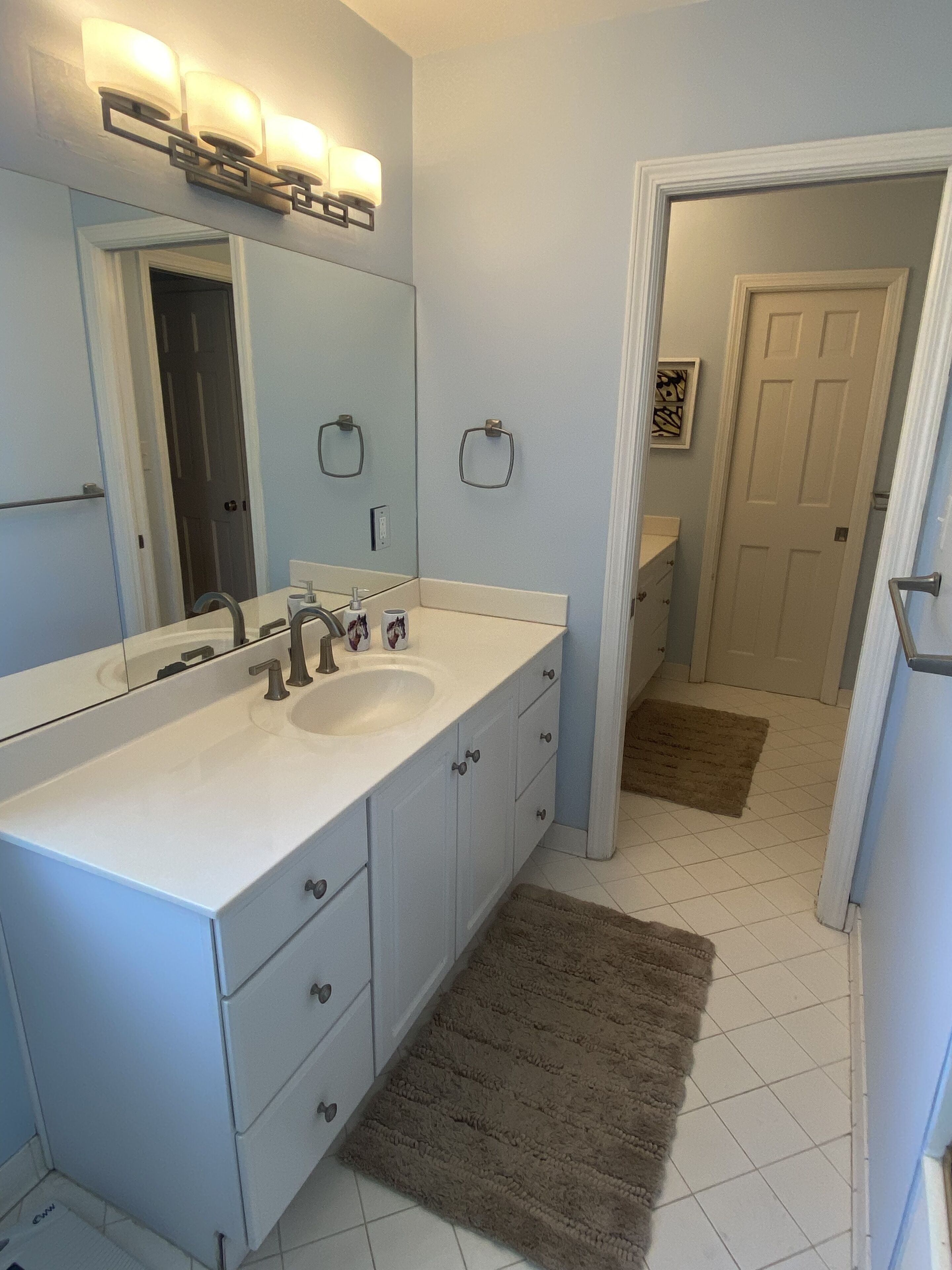 A bathroom with a double sink, a large mirror, and a towel rack.
