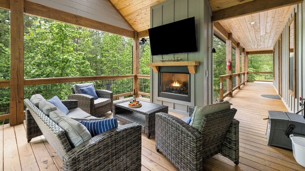 A covered deck with wicker furniture, a fireplace, and a television. - Beyond Pines. Family-Friendly Escape & Retreat (Broken Bow)