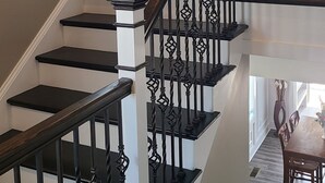 Una scala con ringhiere nere e gradini bianchi, che conduce a un secondo piano.