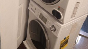A stacked washer and dryer unit with a control panel and safety labels. - Warm apartment with a bus stop at its doorstep (Montreal)