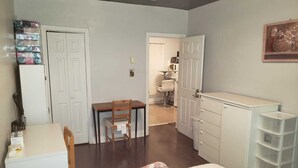 A compact room with a bed, a desk, a chair, a wardrobe, and a bathroom visible through an open door. - Warm apartment with a bus stop at its doorstep (Montreal)