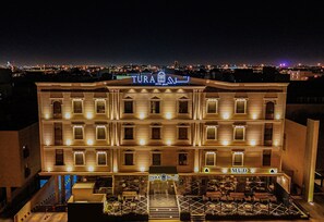 Un hotel con un letrero que dice "TURA HOTEL" y "MUD" en la planta baja.