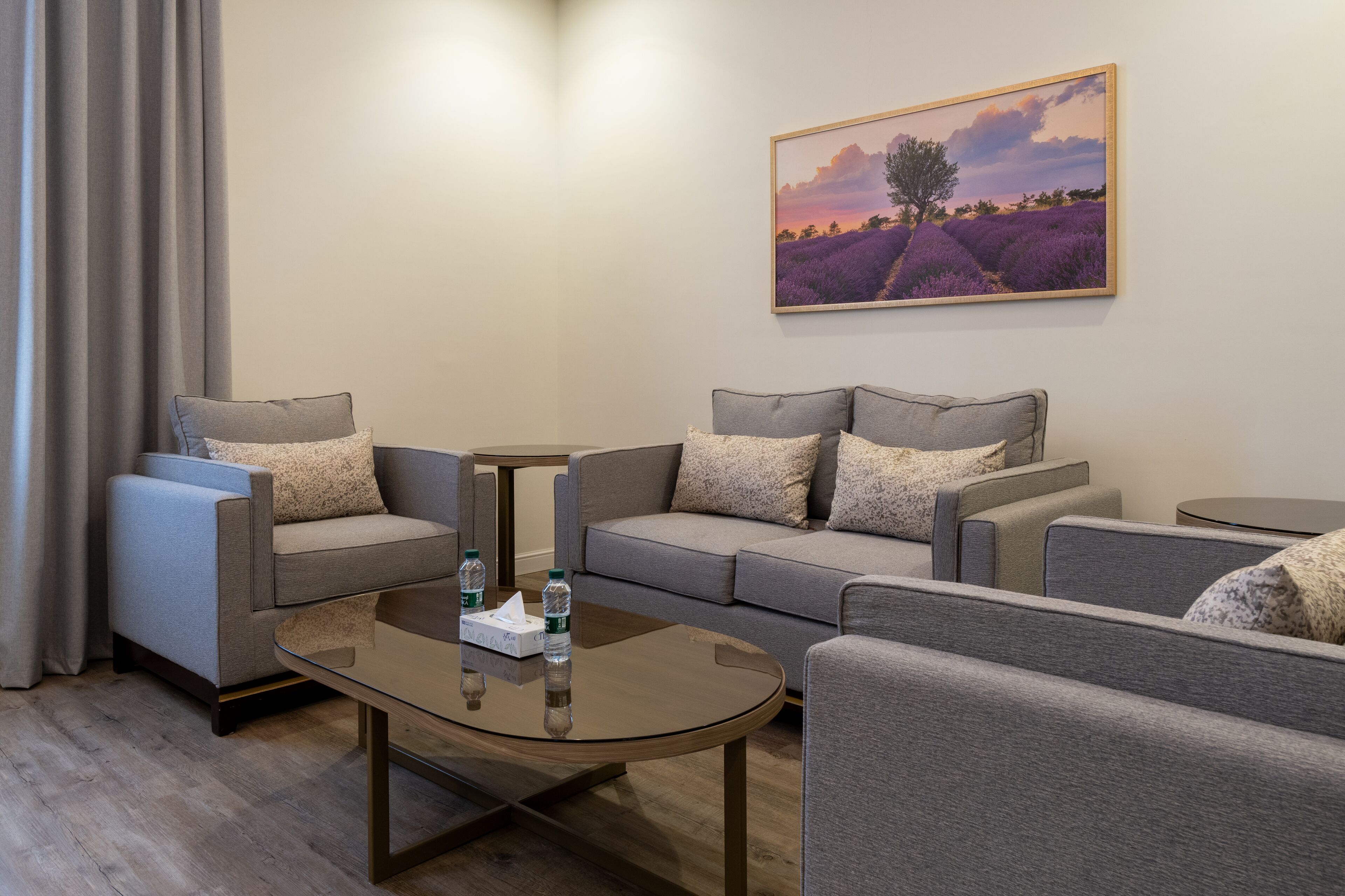 A modern living room with a sofa set, a coffee table, and a painting on the wall.