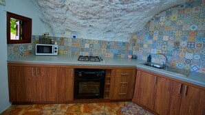A kitchen with a tiled backsplash, wooden cabinets, a microwave, a gas stove, and a sink.