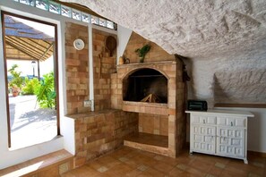 Una chimenea de piedra con un reloj, un mueble blanco y vistas a la vegetación.