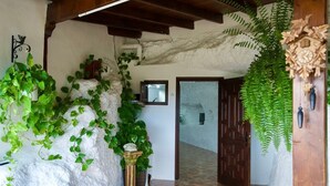 A hallway with a tiled floor, a wooden door, and green plants.