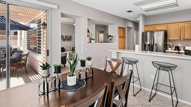 Una cocina moderna con comedor, que incluye una mesa de madera, taburetes de bar y una isla de cocina.