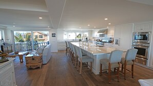 Una cocina amplia con una isla grande, armarios blancos y electrodomésticos modernos.