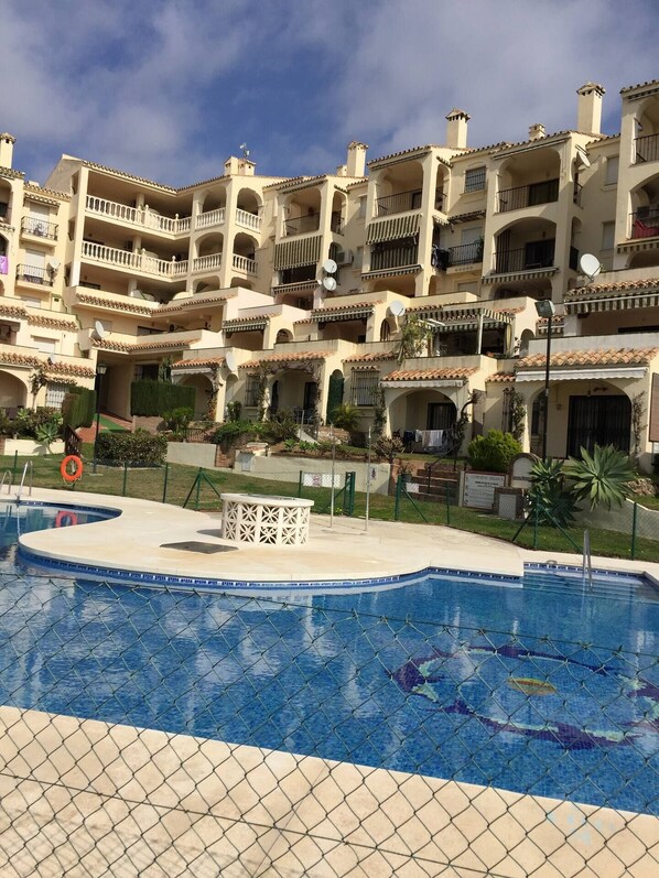 A hotel with a swimming pool, multiple balconies, and a well-maintained garden.