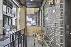 Ein modernes Gebäude mit einem Balkon, zwei Korbstühlen und einer Ziegelwand.