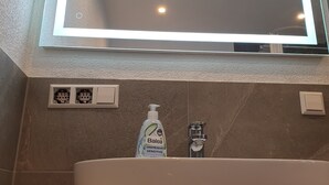 Un ba ño con un espejo grande, un lavamanos blanco y una crema Balea.