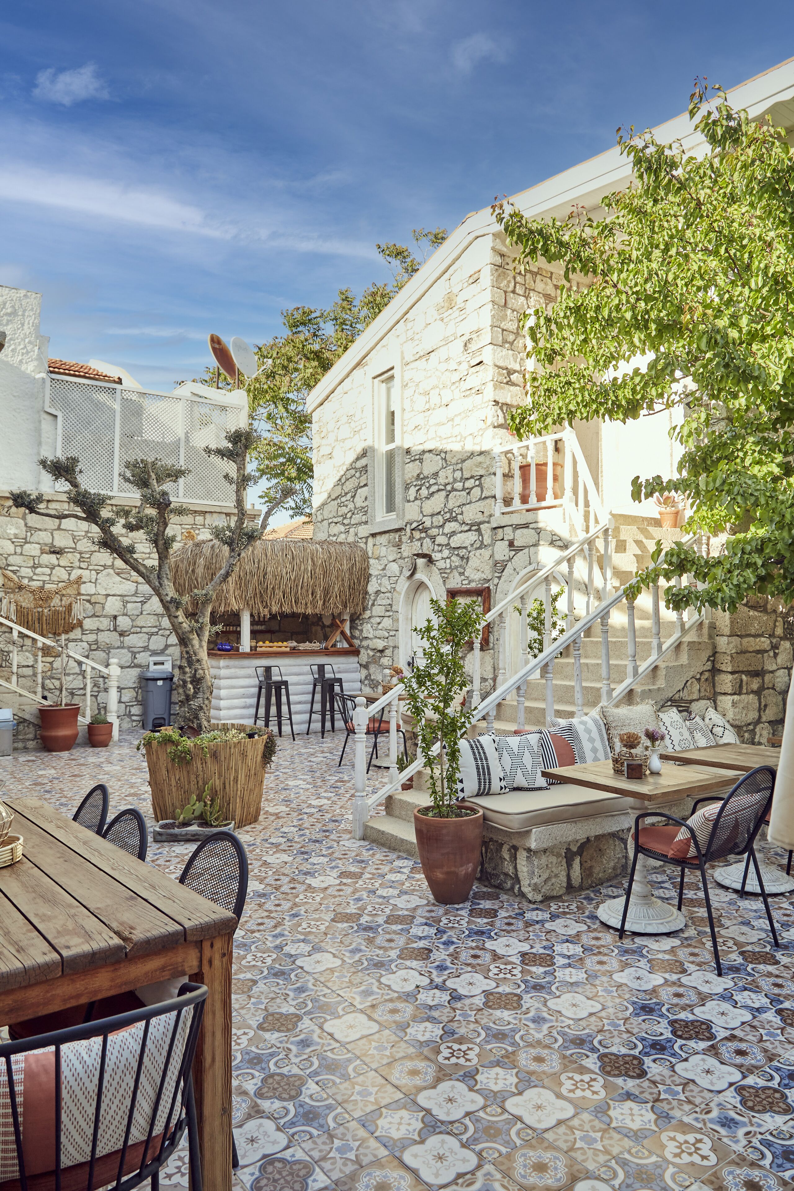 A stone building with a tiled patio, outdoor seating, and a staircase leading to an upper level.