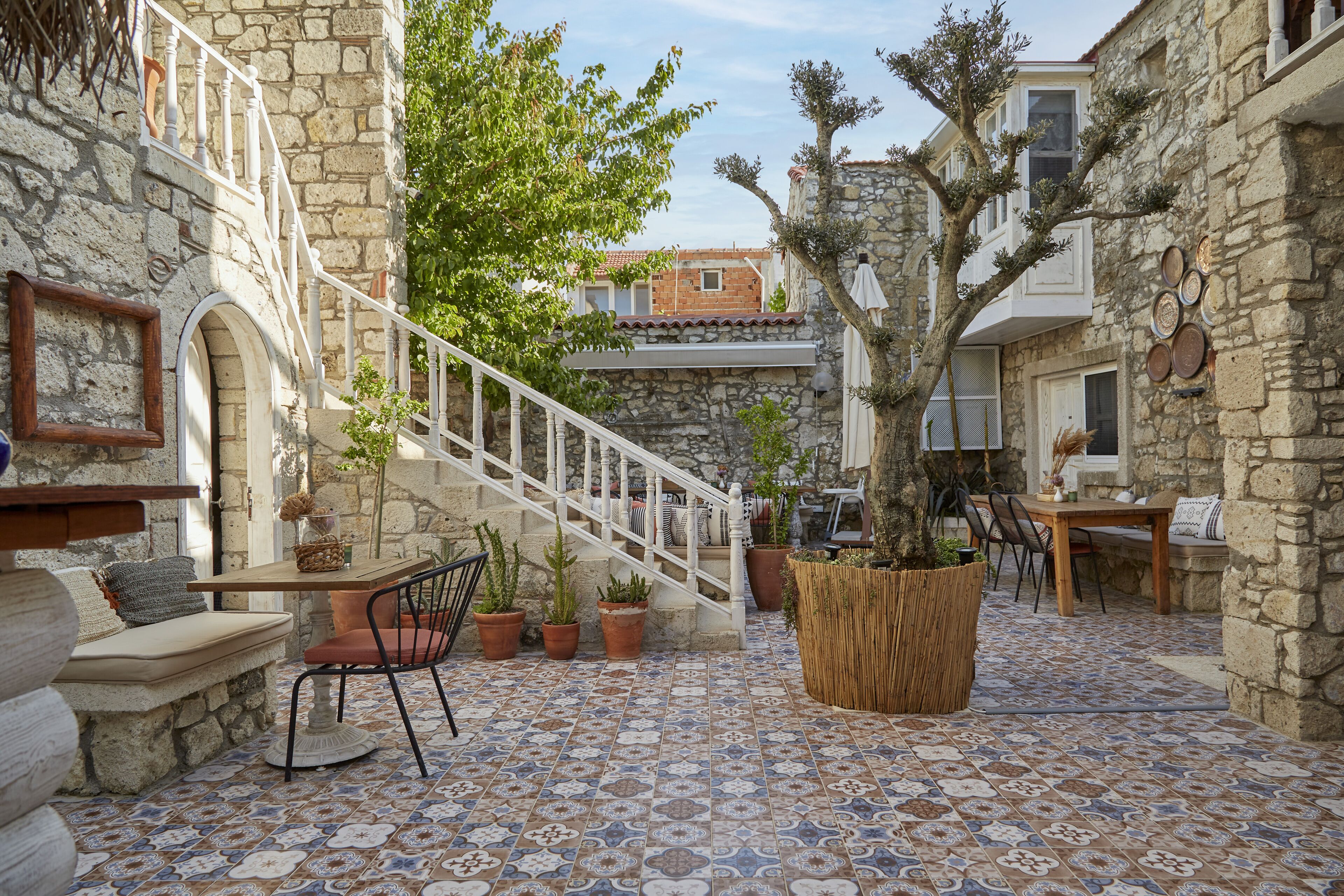 Un patio con muros de piedra, una escalera de madera y plantas en macetas.