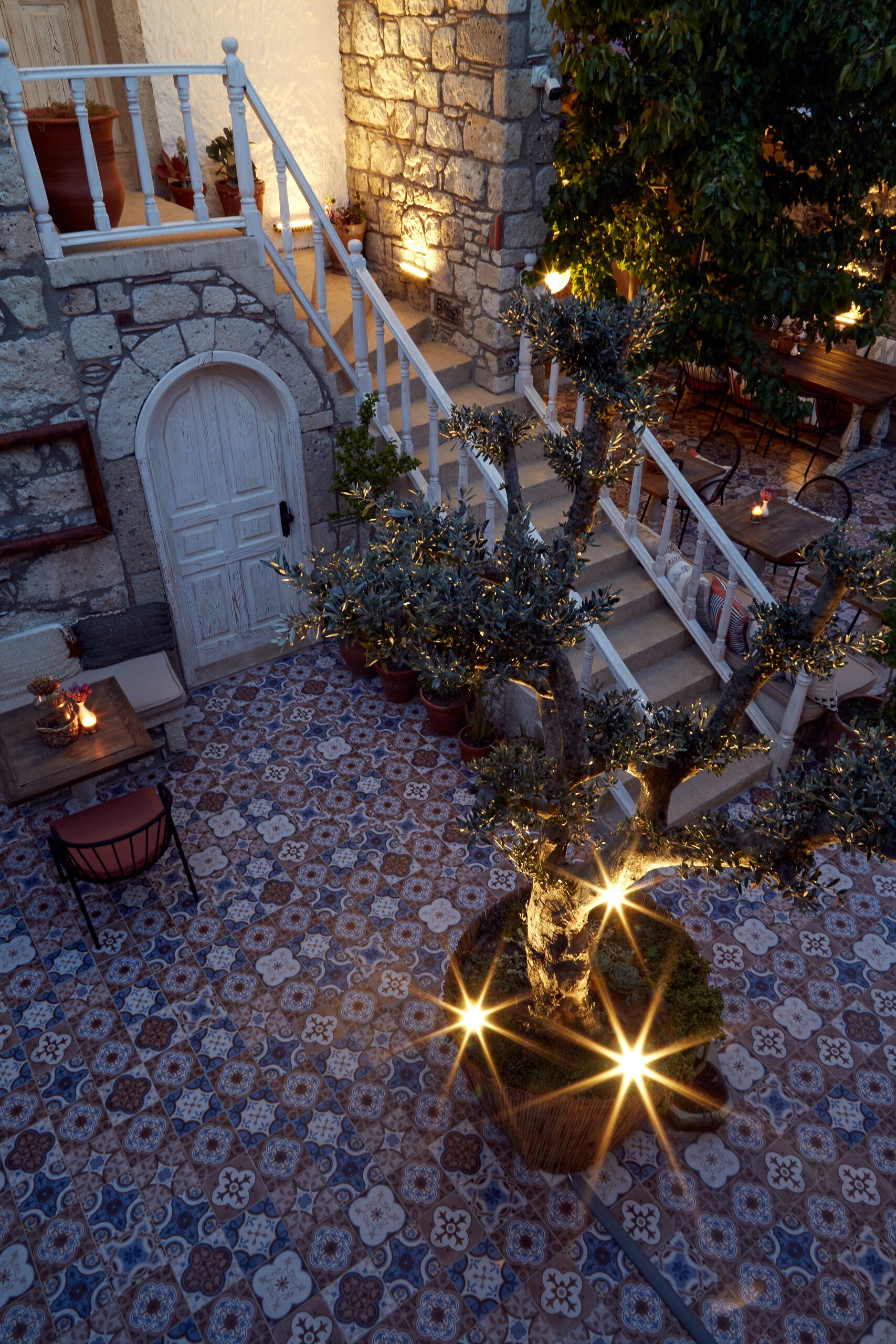 A courtyard with a stone staircase, potted plants, and a tiled floor.