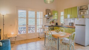 A kitchen with green cabinets, a white refrigerator, and a dining table with chairs.