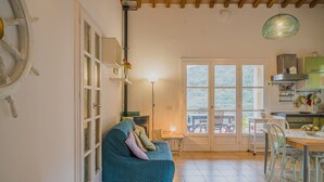 A cozy living room with a blue sofa, a dining area with a table and chairs, and a kitchen with cabinets and a stove.
