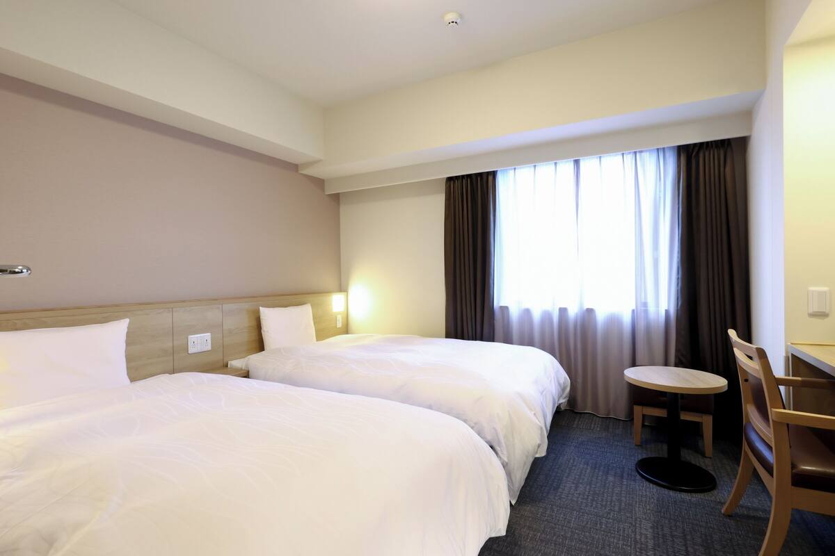 Una habitación de hotel con dos camas, una mesita redonda y una silla.