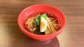 Un tazón de ramen con fideos, un huevo pasado por agua y alga sobre una mesa de madera.