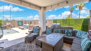Un patio extérieur couvert avec une piscine, un espace salon et un barbecue.