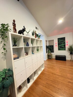Una habitación amplia con un mueble blanco para guardado, suelo de madera y un ventanal grande.