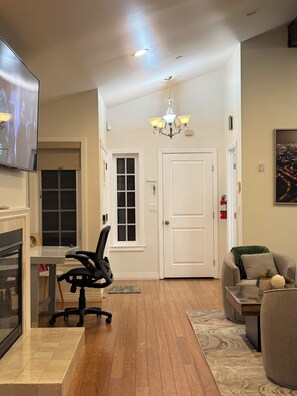 A modern living room with a fireplace, a dining area, and a kitchen.